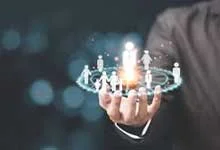 A person in a suit holds a holographic circle displaying diverse human figures, symbolizing connectivity and technology, set against a blurred dark background.