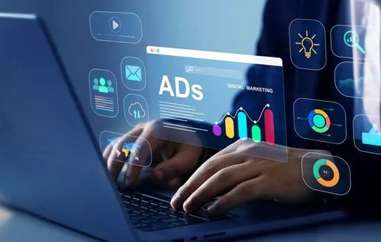 Person typing on a laptop displaying digital marketing graphics, including graphs and icons, conveying a theme of online ads and analytics.