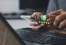Person using a smartphone above a laptop with digital interface showing a green chat icon and five-star rating. Modern technology and communication theme.